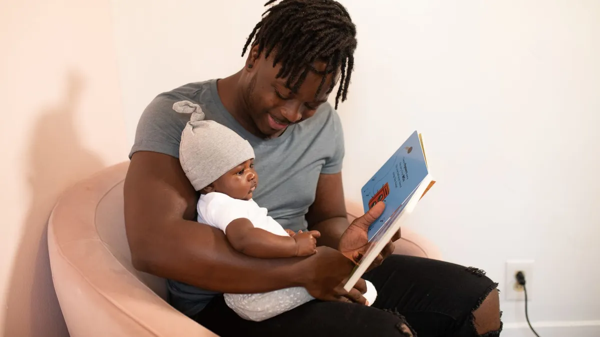Un papa qui lit un livre à son bébé, complicité père-enfant