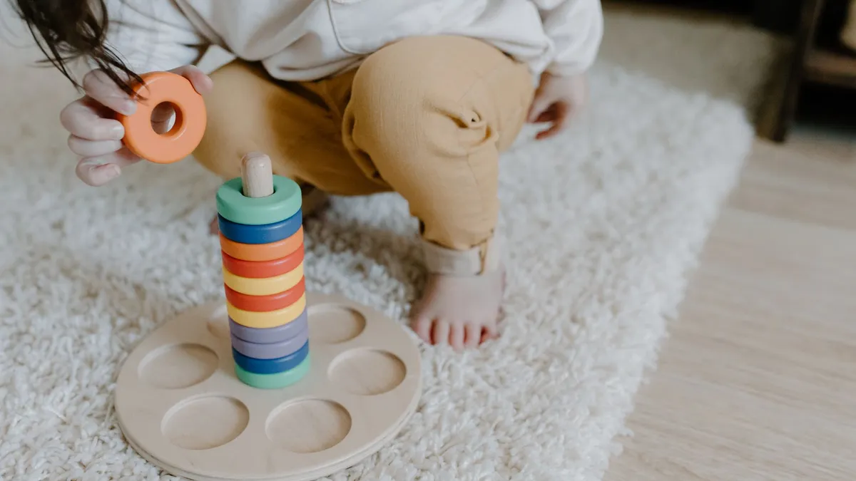 Main d'enfant qui manipule un jouet d'empilement en bois de type matériel Montessori