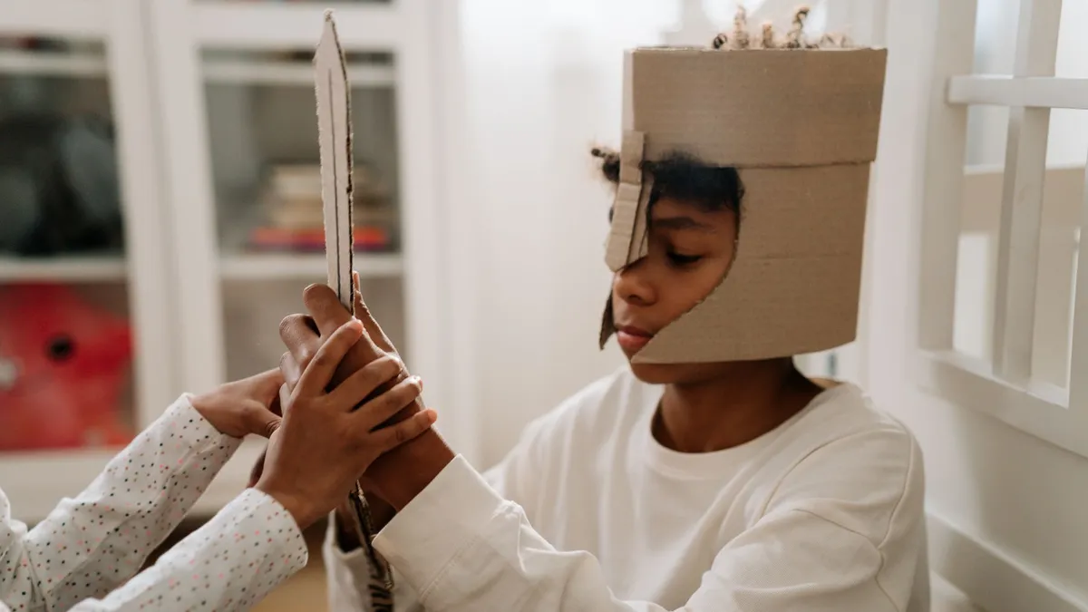 Enfant costumé en chevalier jouant avec un accessoire en carton