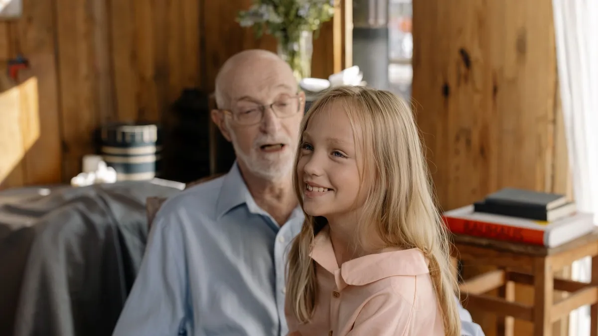 Une petite fille assise sur les genoux de son grand-père